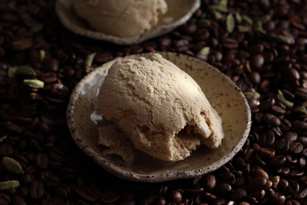 Mokka-Eis mit Kardamom in einem Schälchen auf Kaffeebohnen serviert.