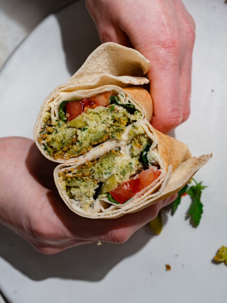 Halbierter Falafel Wrap: beide Hälften nebeneinander so dass man den Inhalt sehen kann.