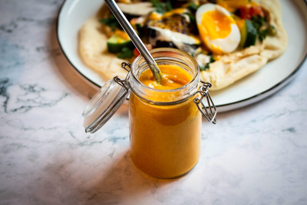 Sauce amba servie à la cuillère dans un verre.