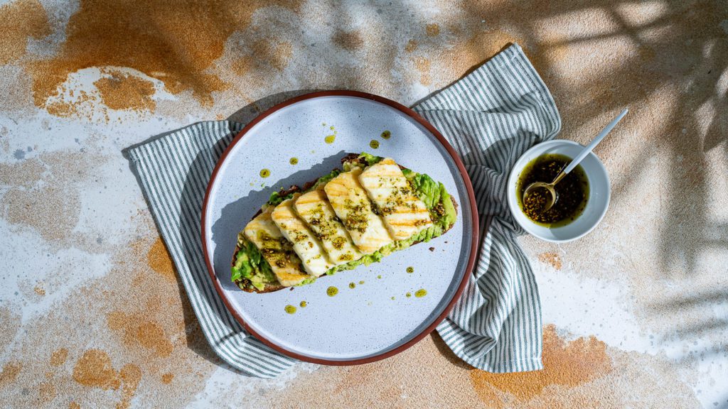 Avocado bread drizzled with halloumi and za'atar oil and served on a plate.