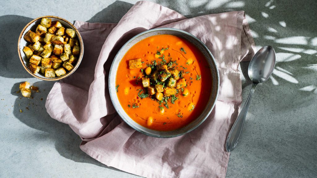 Tomatensuppe mit weißen Bohnen und Za’atar Croûtons, serviert in kleinen Schüsseln.