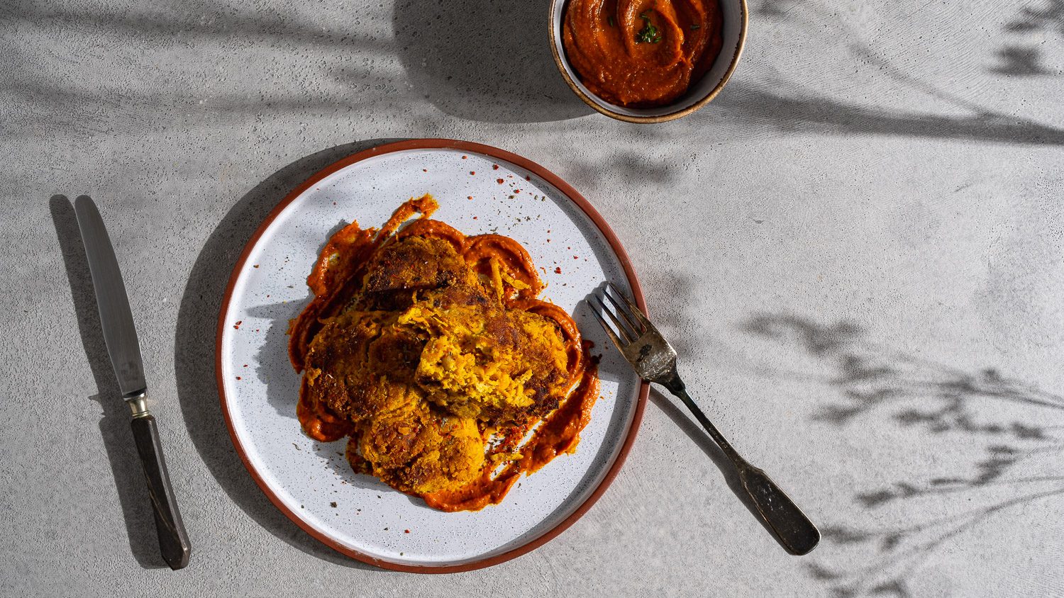 Kichererbsen-Kürbis-Fritters auf Paprika-Kürbis-Dip serviert.