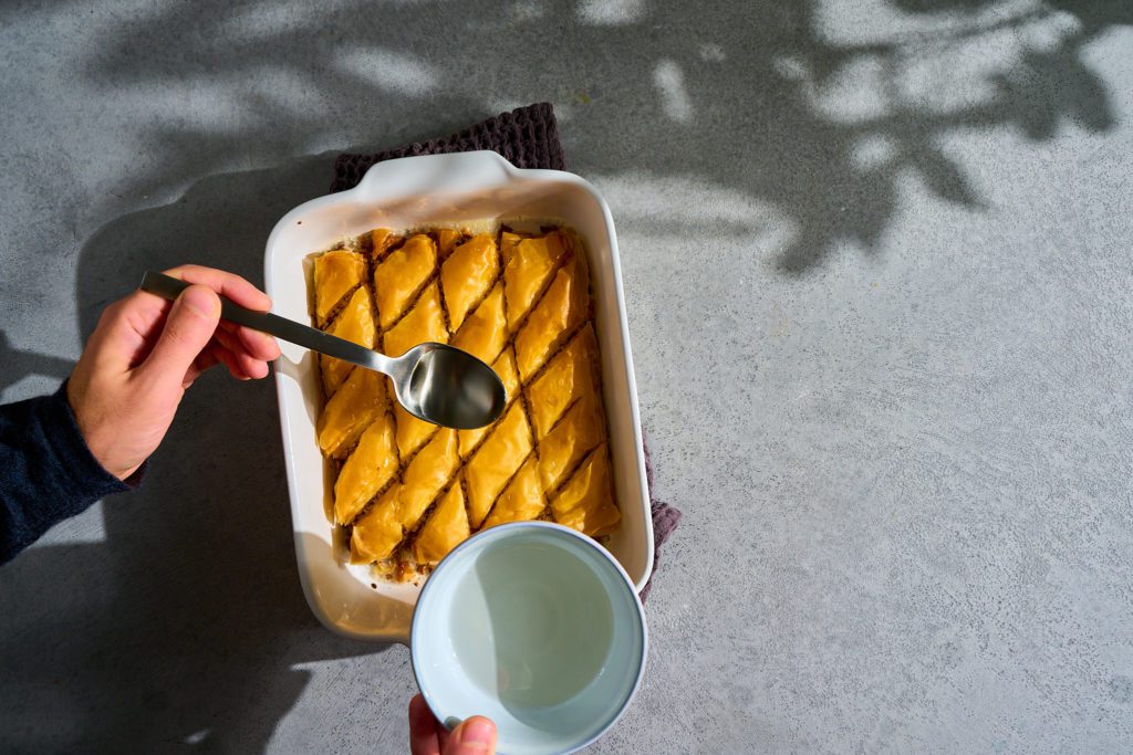 Baklava Rezept: Heißes Baklava in einer Auflaufform wird mit Sirup übergossen.