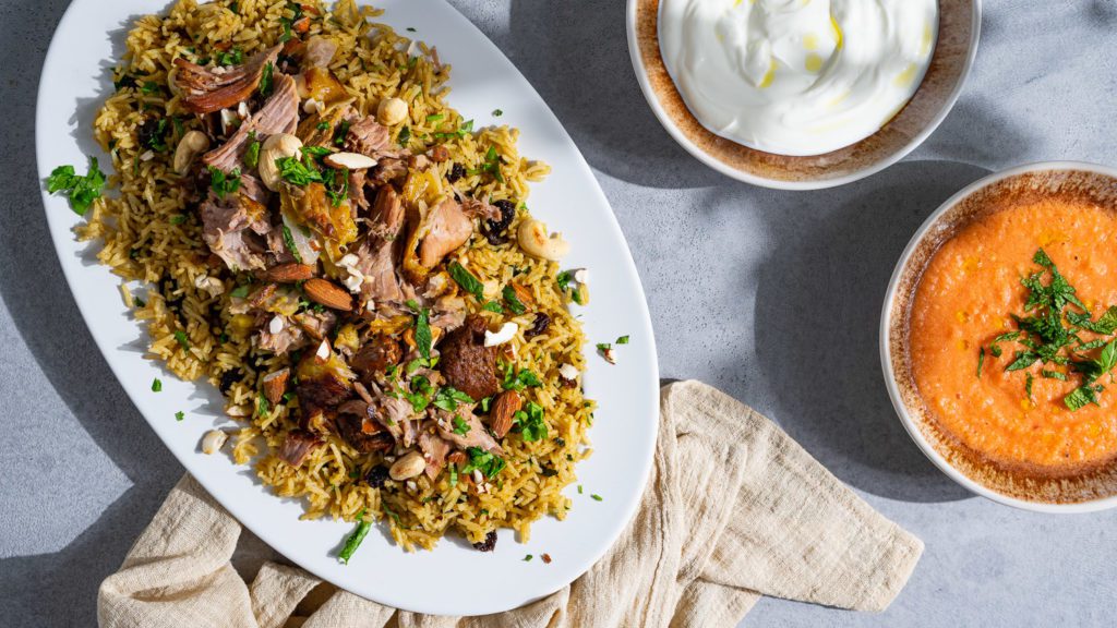 kabsa - reis mit lamm auf ovelaem teller serviert mit joghurt und tomatensalsa