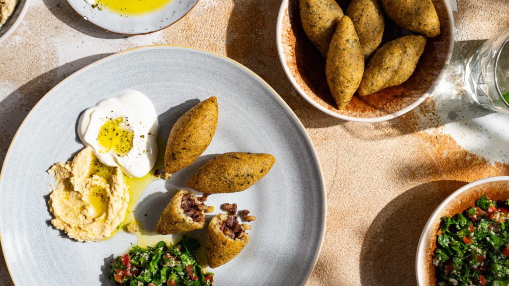 Kartoffel Kibbeh Kroketten, serviert mit kleinen Mezze-Schälchen.