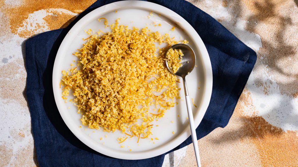 Bulgur de mantequilla servido con cuchara en un cuenco de mármol.