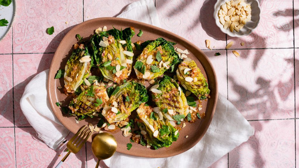 Gegrillte Salatherzen mit feuriger Vinaigrette auf einem großen Teller serviert.