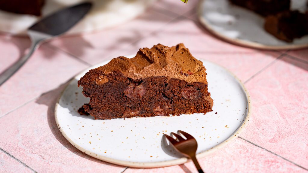 Ein Stück Schoko-Kirsch-Kuchen auf einem Teller mit Gabel serviert.