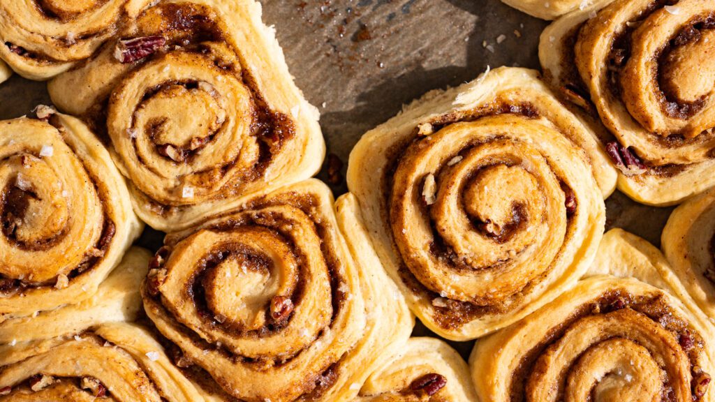 Vegane Zimtschnecken liegen frisch gebacken auf einem Blech.