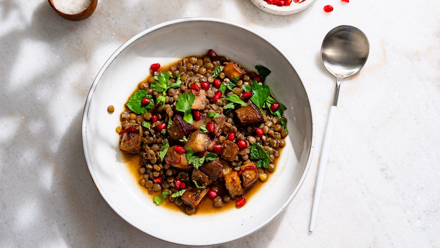 Lentil eggplant stew served in a deep plate. There is a spoon next to it.