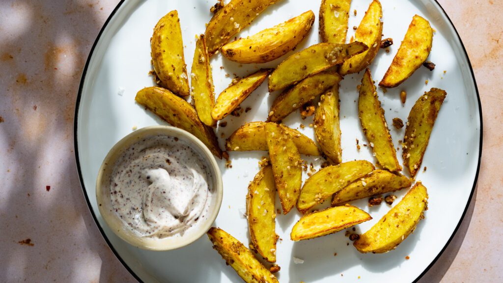 Des pommes de terre au four saupoudrées de dukkah et servies avec de la mayo au sumac.