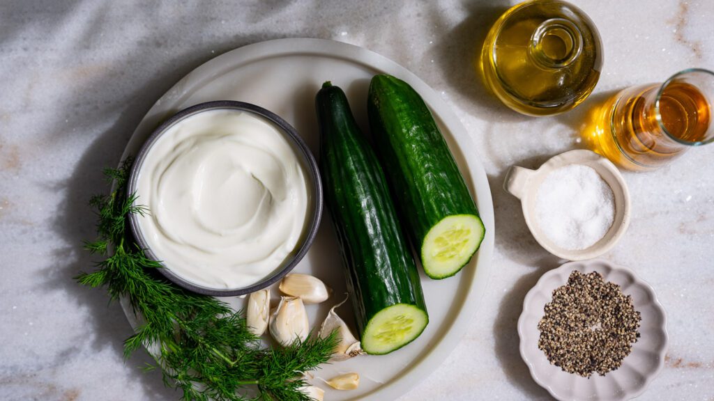 Los ingredientes para el tzatziki se extienden sobre una base de mármol claro.