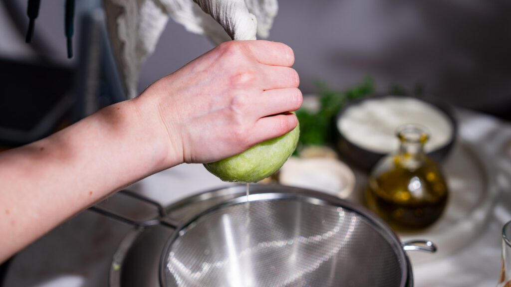 Un pepino rallado se escurre en un paño colador para el tzatziki griego.