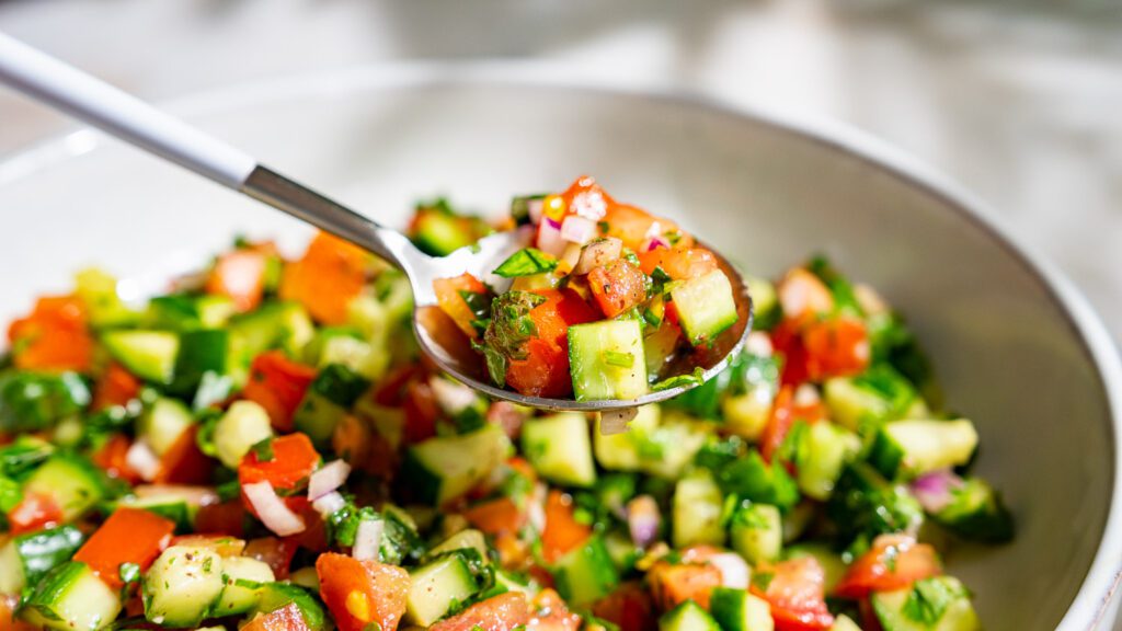 Shirazi Salat wird mit einem Löffel aus einer Schüssel genommen.
