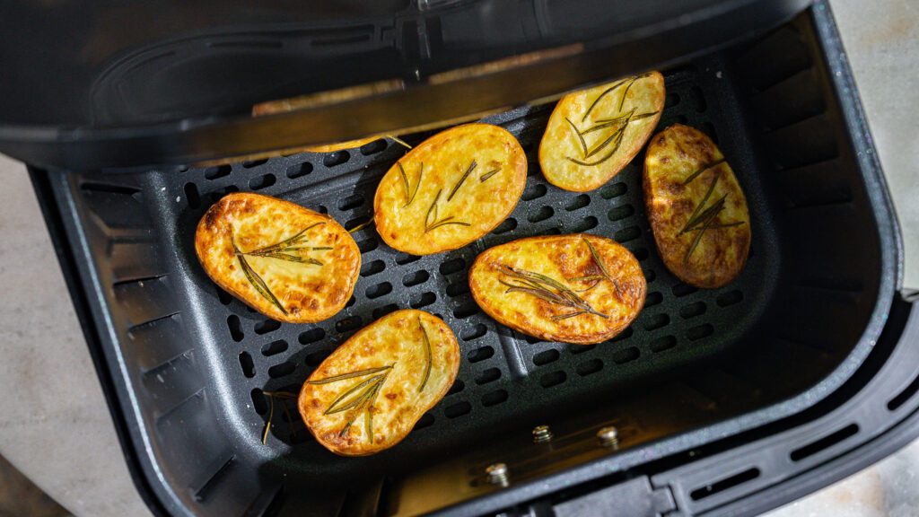Rosemary potatoes are still in the basket of the air fryer.