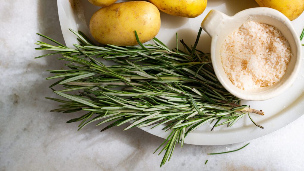 Rosemary and salt on a tray for rosemary potatoes.
