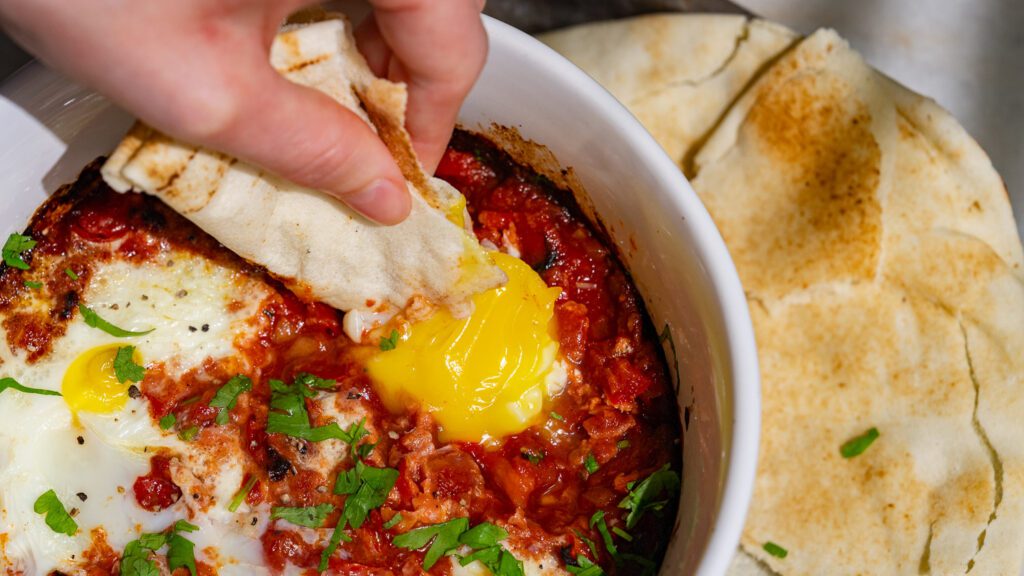 Shakshuka aus der Heißluftfritteuse wird mit einem Fladenbrot gedippt.
