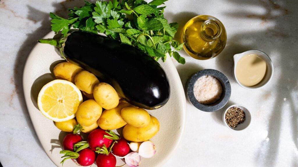 Los ingredientes para la Ensalada de patatas trituradas con crema de berenjena están sobre la mesa.