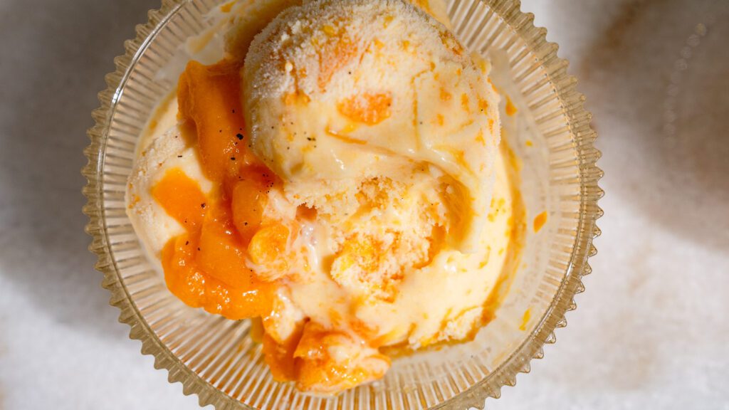 Helado de albaricoque servido con yogur en un cuenco de cristal.