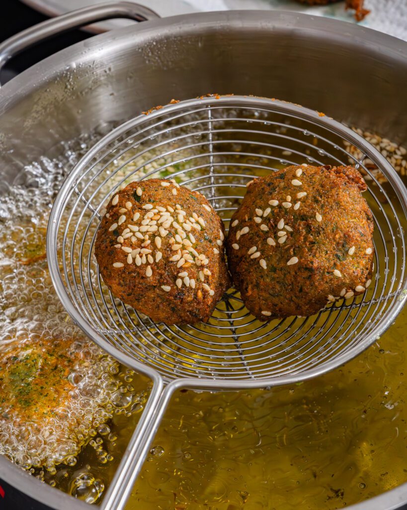 Ta'amia fraîchement frit dans une écumoire au-dessus de la friteuse.