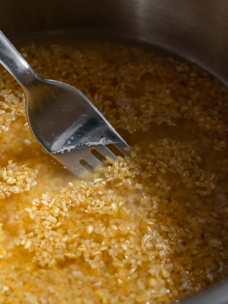 Cook the bulgur - stir the bulgur with a fork in a pot of hot water so that it can cook.