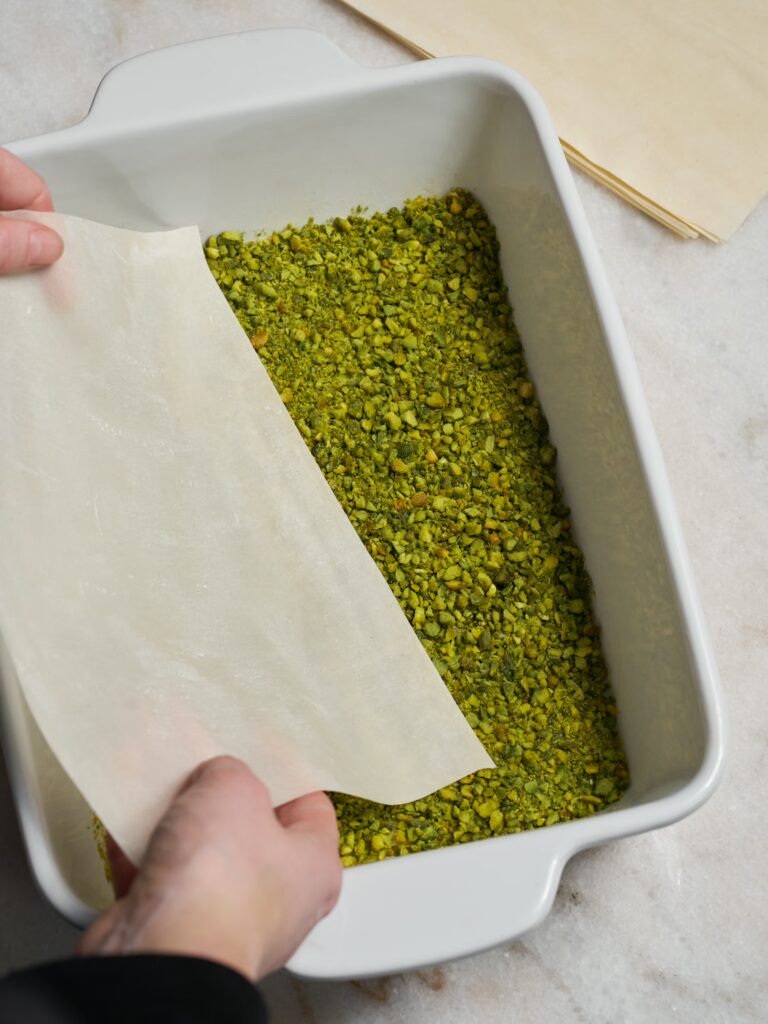 Eine weiter Schicht Filoteig wird auf die Pistazienfüllung für das Pistazien-Baklava in die Form gelegt.