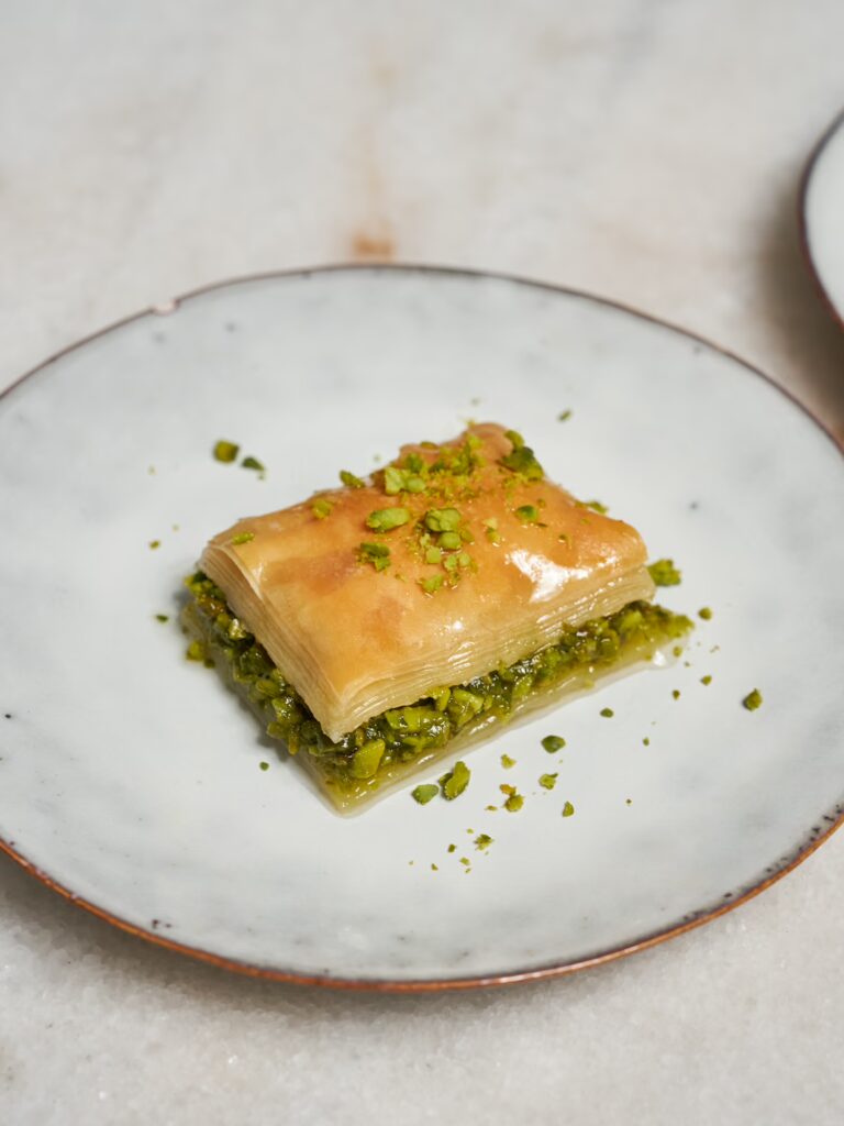 Ein Stück Baklava mit Pistazien auf einem Teller serviert.