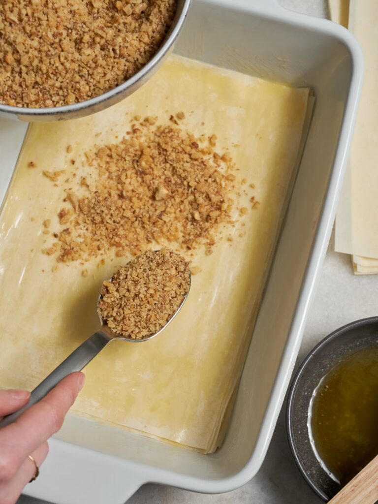 Filoteigschichten werden mit gerösteten Walnüssen bestreut für das Walnuss Baklava.