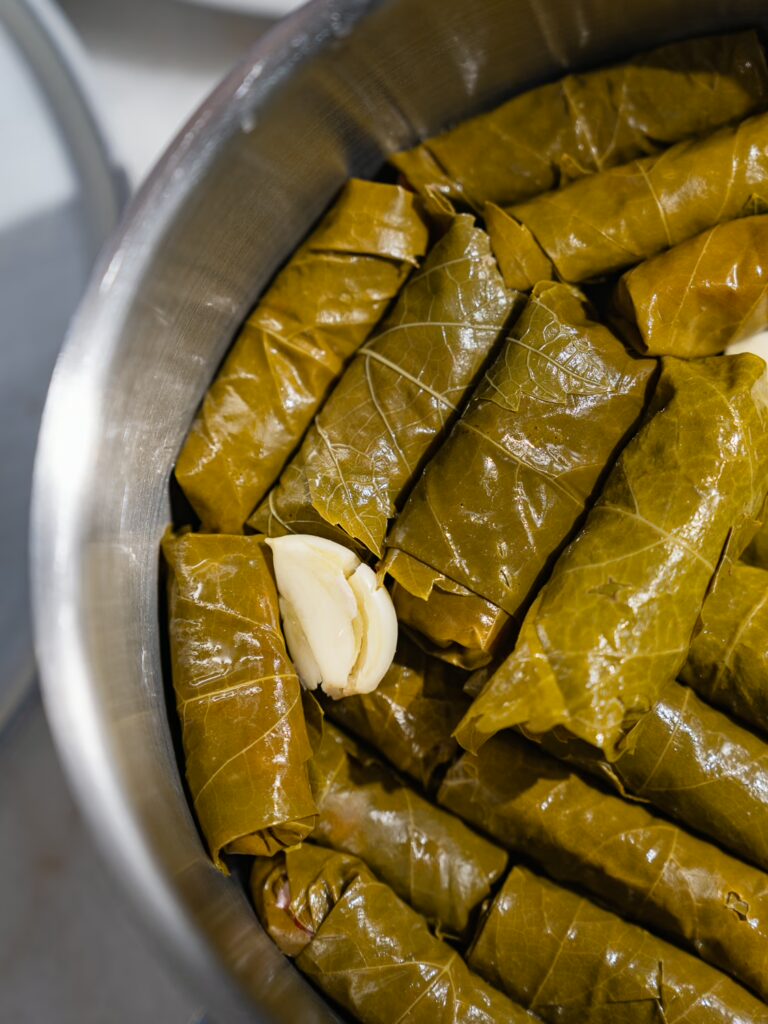 Garlic is inserted between the layers of vine leaves filled with minced meat.