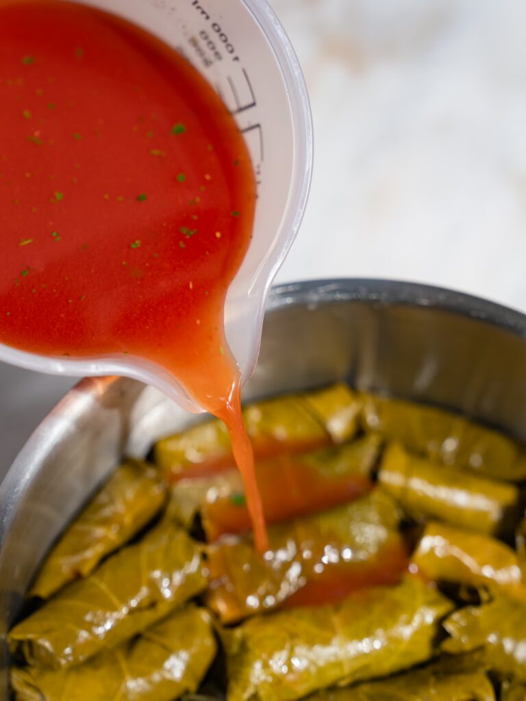 Stuffed vine leaves with minced meat are infused with tomato broth.
