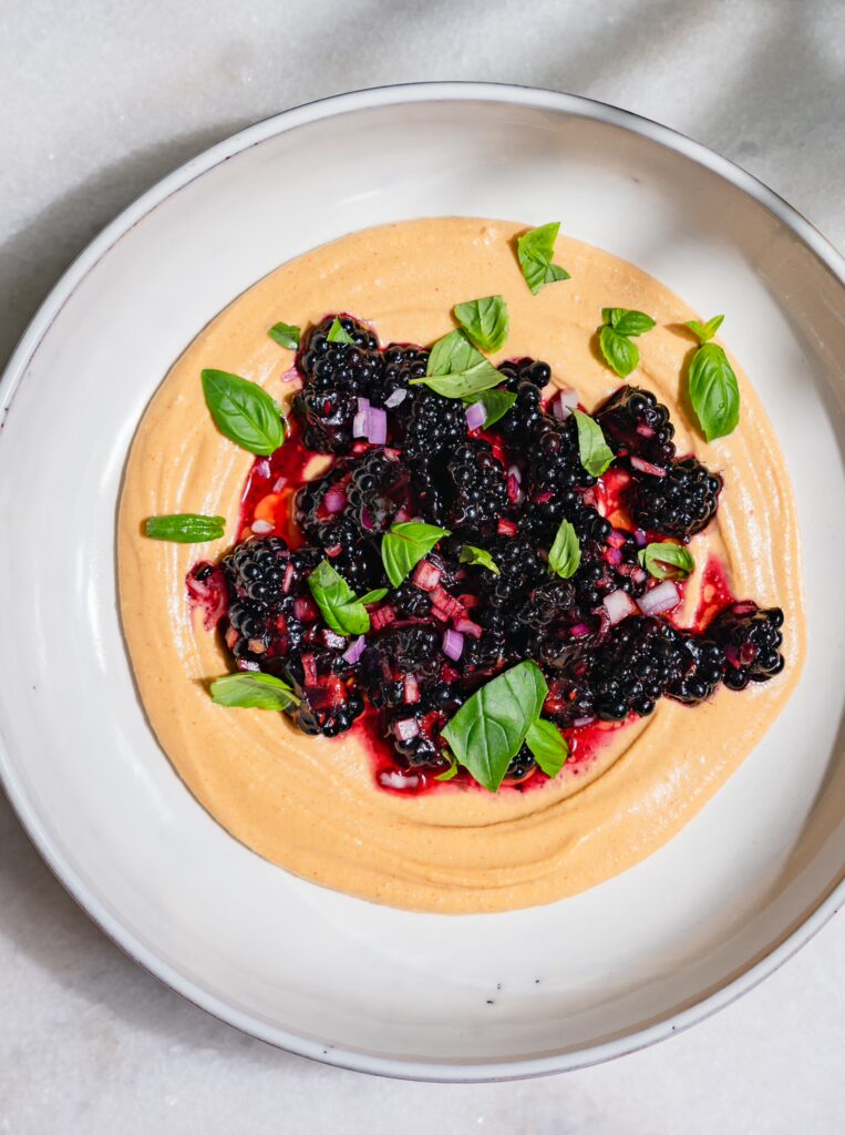 Ein Salat aus Brombeeren ist auf cremiges Hummus mit Gochujang gebettet.