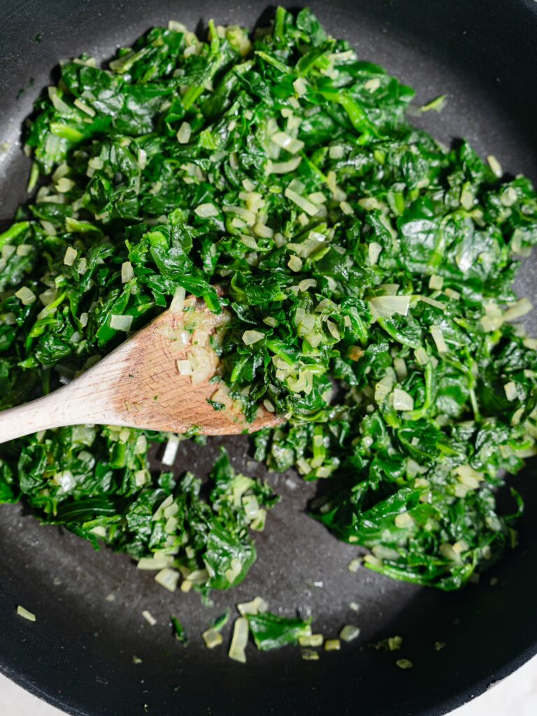Les épinards sont sautés dans une poêle pour pâte feuilletée avec des épinards et de la feta.