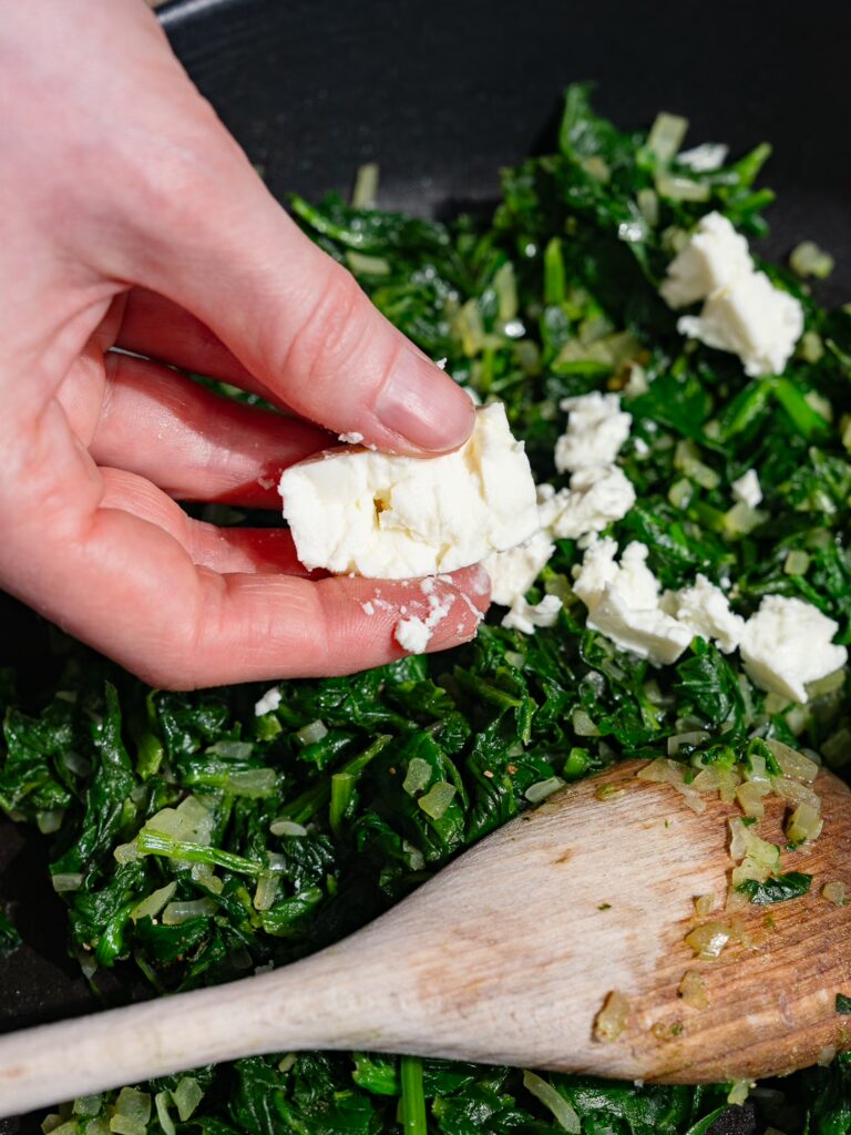 La feta est émiettée dans la poêle avec les épinards pour les feuilletés.