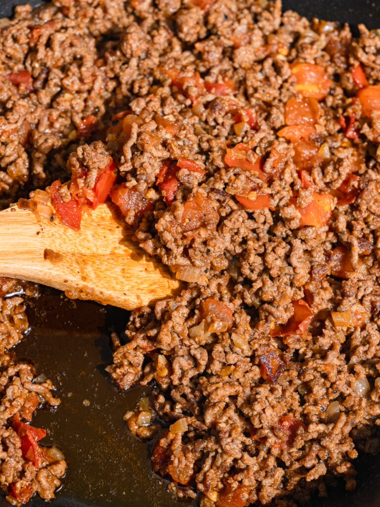Ready-made sauce for börek with minced meat is stirred with a spoon.