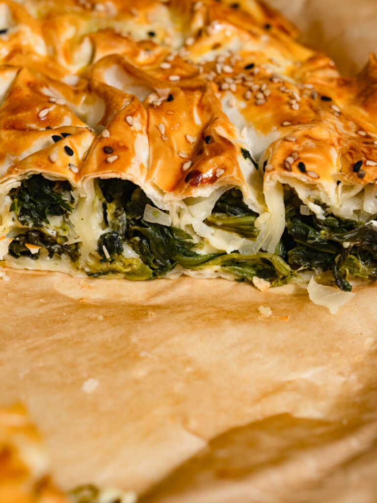 Rebanadas de börek con espinacas sobre papel de horno.
