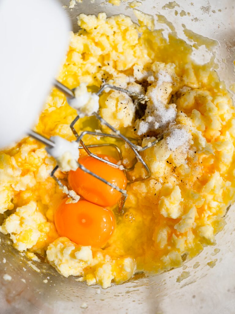 La mantequilla, el azúcar y los huevos se mezclan en un bol con una batidora de mano para obtener el húmedo pastel marmolado de la abuela.