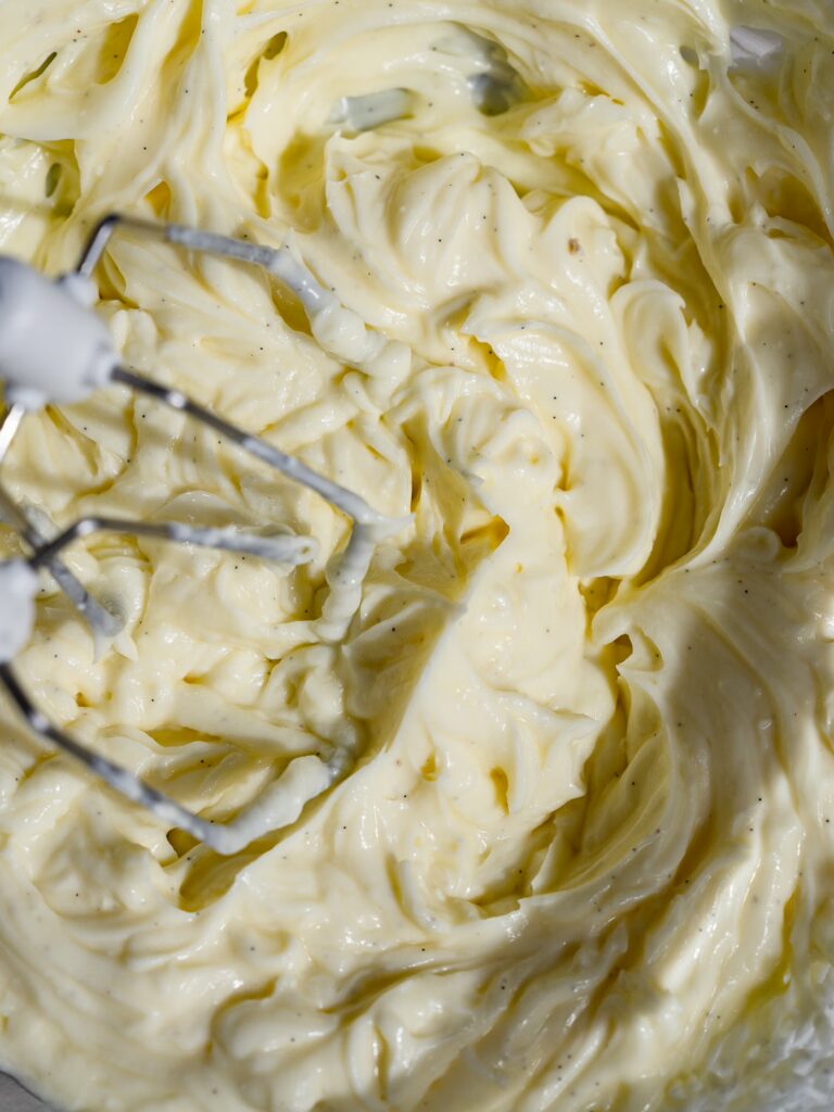 Frischkäse Frosting für einen saftigen Karottenkuchen wurde gerade mit einem Handmixer vermengt.