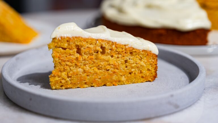 Una porción de tarta de zanahoria húmeda con glaseado servida en un plato.