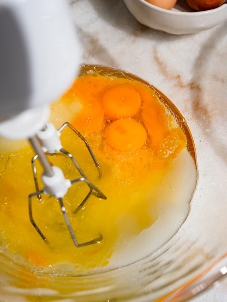 Eier, Zucker und Öl werden in einer Glsschschüssel mit einerm Handmixer geschlagen.