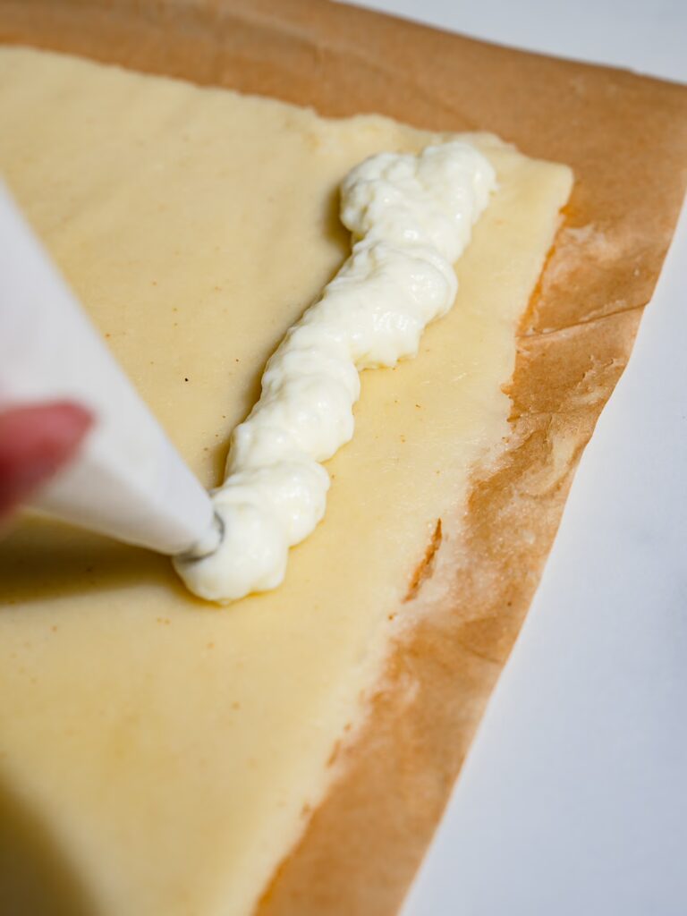 Aplica el relleno de crema pastelera a la masa con una manga pastelera.