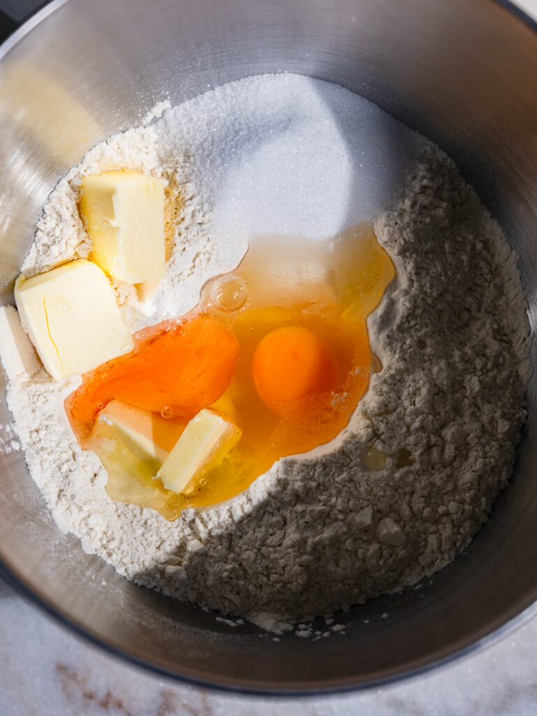 Mehl, Zucker, Eier, Butter und Salz für den Hefeteig in einer Schüssel.