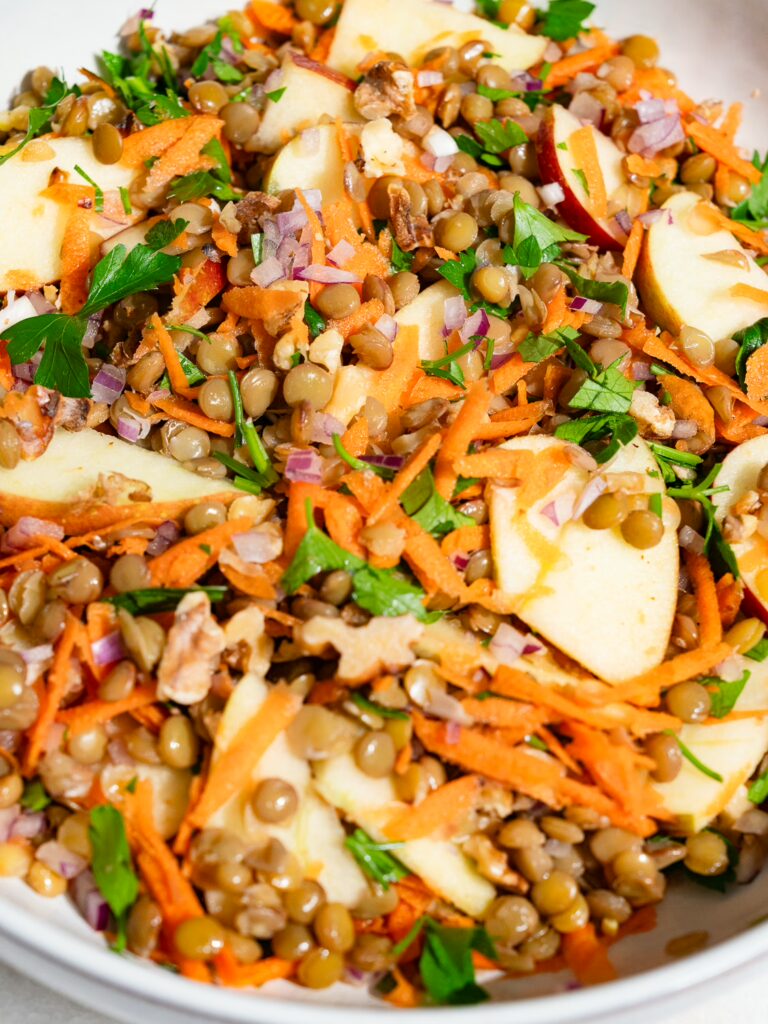 Salade de lentilles avec pomme et vinaigrette mélangées et servies dans un saladier.
