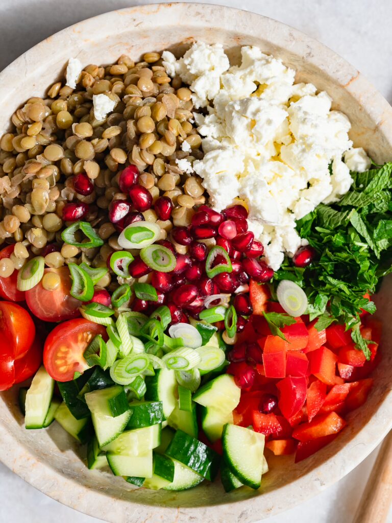Tous les ingrédients de la salade de lentilles orientale sont coupés dans un bol.
