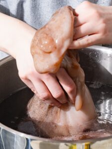 Der Oktopus wird am Kopf in das heiße Wasser getaucht.